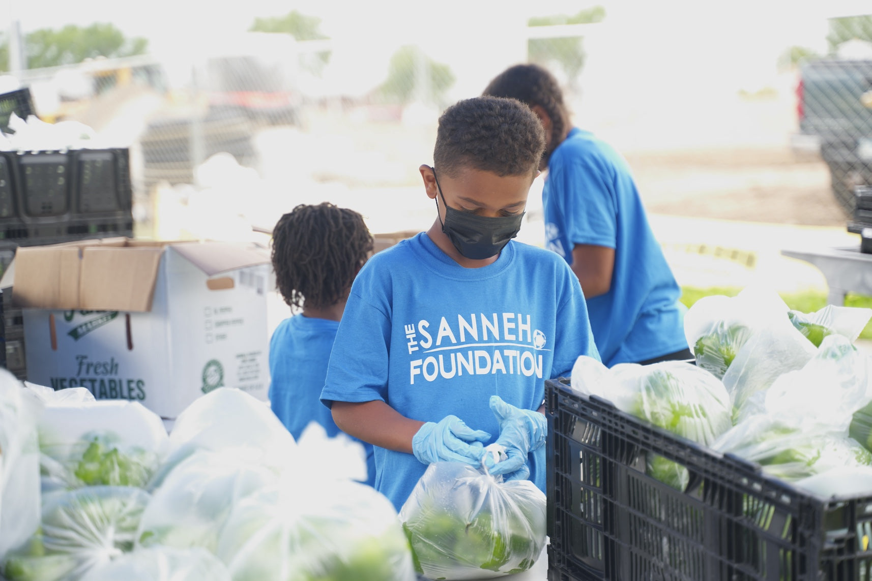 A child volunteer bagging The Black Radish produce for The Sanneh Foundation food program.