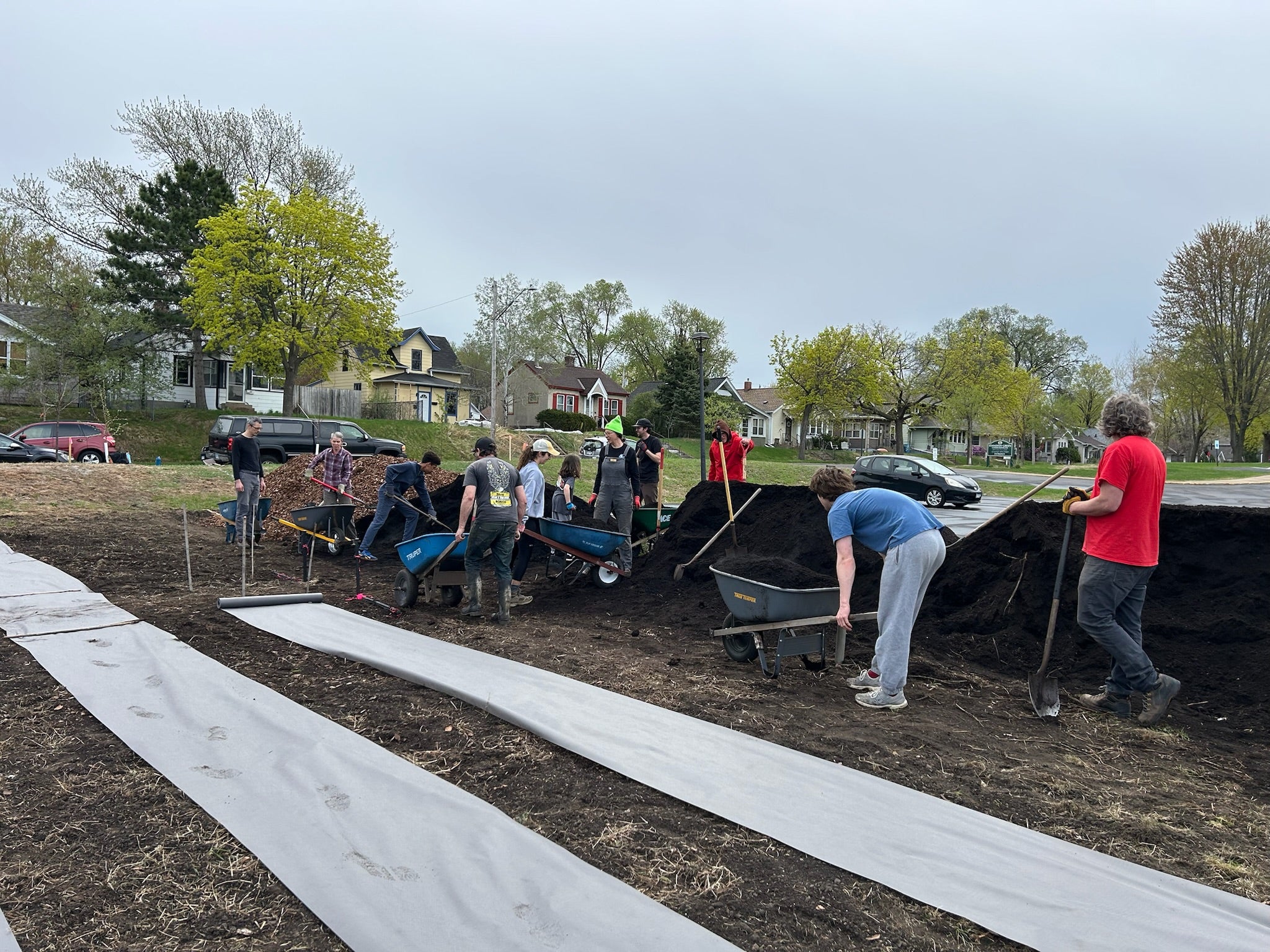 Group of people working with wheelbarrows and shovels to build The Black Radish Urban Farm in Minneapolis.